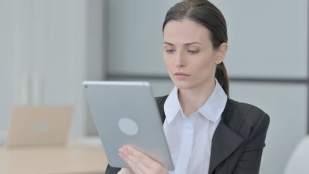 istock Businesswoman Browsing Internet on Digital Tablet 1472854933