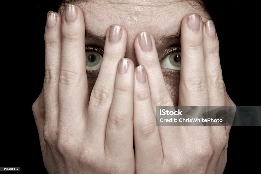 Fear Woman peers through her fingers. Fear Stock Photo