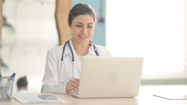istock Young Indian Doctor Doing Online Video Chat in Clinic 1472856698