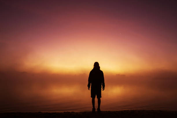 Silhouette of man against background of morning sky. Sunset stock photo