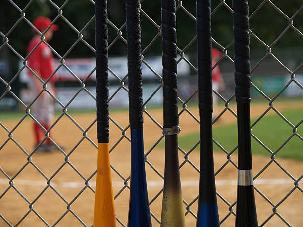 baseball bats on fence, players in background stock photo