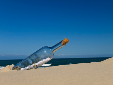 A bottle with a message inside is buried on the beach.