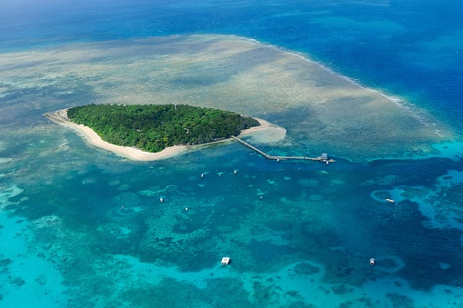 An aerial view of the coral reefs and clear turquoise waters surrounding Green Island, a small tropical isle in the outer Great Barrier Reef off the coast of Cairns