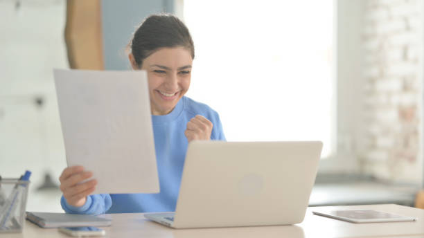istock Indian Woman Celebrating Success while Doing Paperwork 1472859998