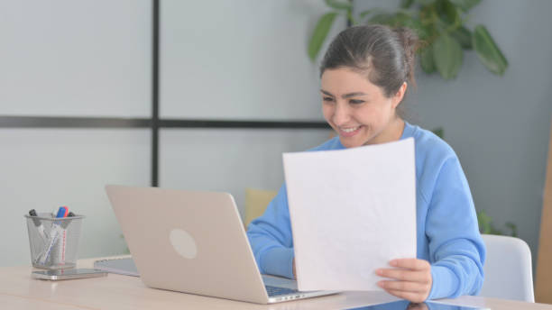 istock Indian Woman Celebrating Success while Doing Paperwork 1472860258