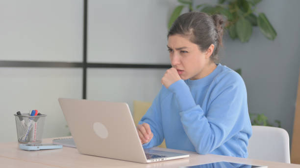 istock Indian Woman Coughing while Working on Laptop 1472860398