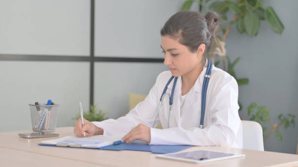 istock Young Indian Doctor Working on Documents in Clinic, Paperwork 1472860535