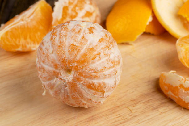istock Peeled orange divided into slices on a board 1472861849