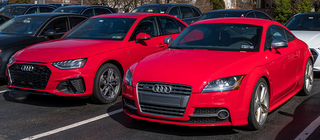 Sewickley, Pennsylvania, USA March 5, 2023 Two new, red Audi vehicles, a sedan and coupe for sale at a dealership on a sunny winter day