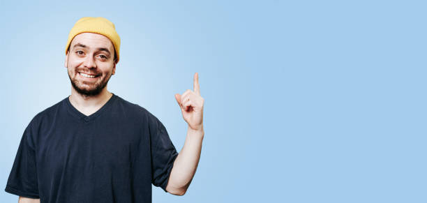 istock A laughing guy in a yellow cap, in a studio shot with the index finger up he has an idea, eurek. 1472865743