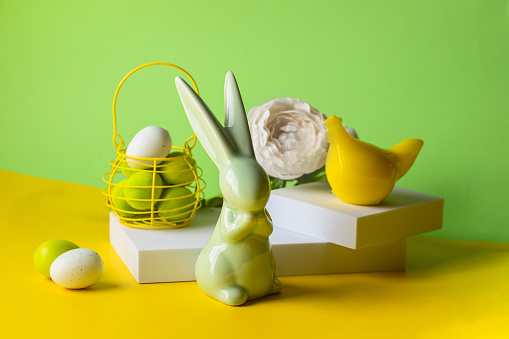 Easter still life. Bunny, hen,eggg on platform  on green yellow background. Minimalist image