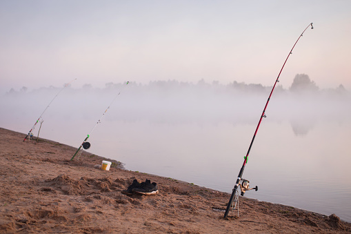 Fly fisherman fishing on the river at foggy sunrise
