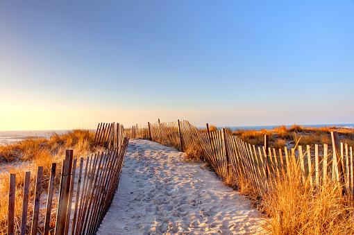 A wooden pathway on the sandy beach at sunset in Maine, USA