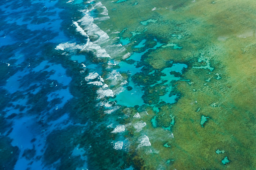 Gentle waves breaking over the coral reefs of the Great Barrier Reef. As seen from a scenic flight over the outer reef near Cairns