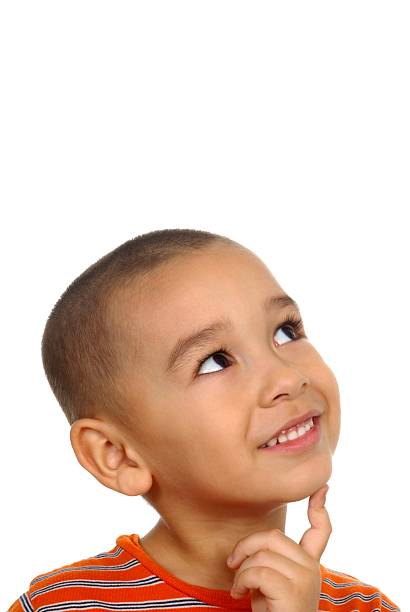 a 5-year-old hispanic boy looking up with a wondering expression and finger on chin, isolated on white background with copy space