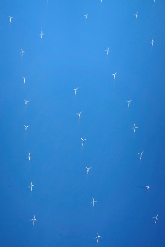 Aerial view of an offshore wind turbine park on a sunny day.