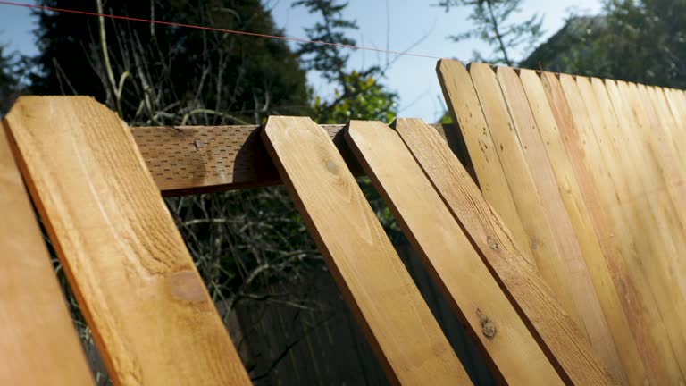 Wood Fence Pickets Lined Up Along an Incomplete Job Site With No Workers