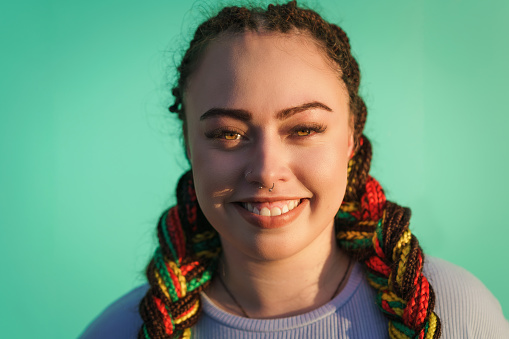 Candid portrait of young Maori woman against light blue backdrop in Auckland, New Zealand.