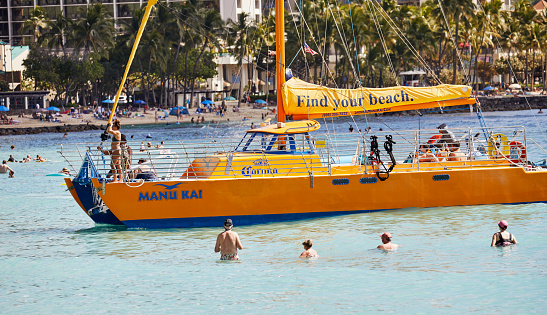 Waikiki, Oahu, Hawaii, USA, - February 6, 2023: A catamaran tour boat filled with tourists in Waikiki