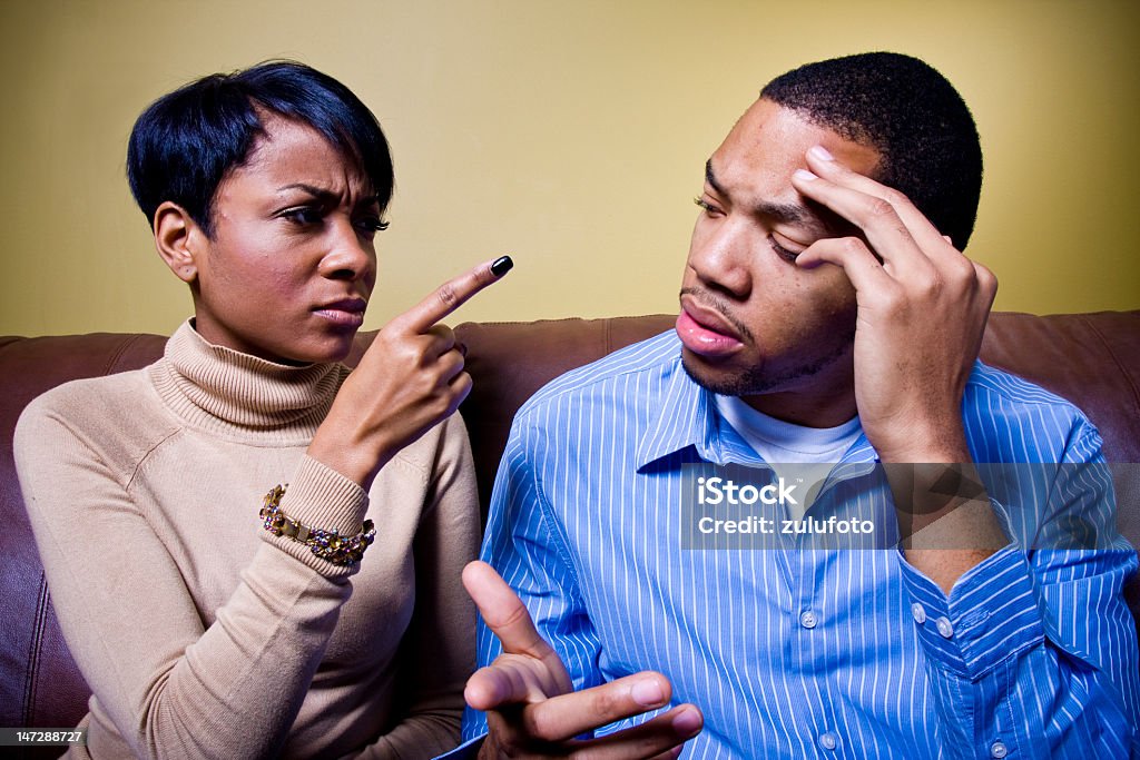 African-American couple arguing A couple is fighting on a couch and the girl is pointing her finger accusingly at him.    Adult Stock Photo