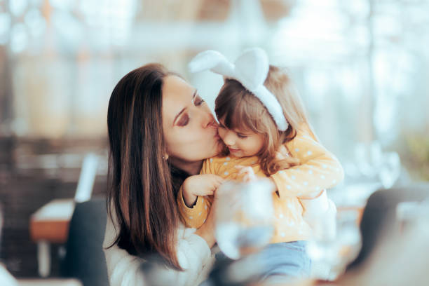 Mother Kissing her Child Wearing Bunny Ears on Easter stock photo