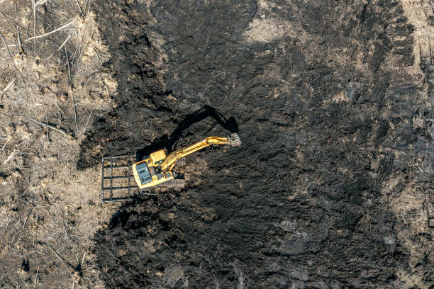 istock yellow working excavator digging black soil or peat. aerial top view from flying drone. 1472896373