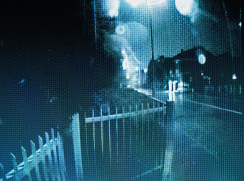 fuzzy still frame from cctv doorbell security camera video during raining night