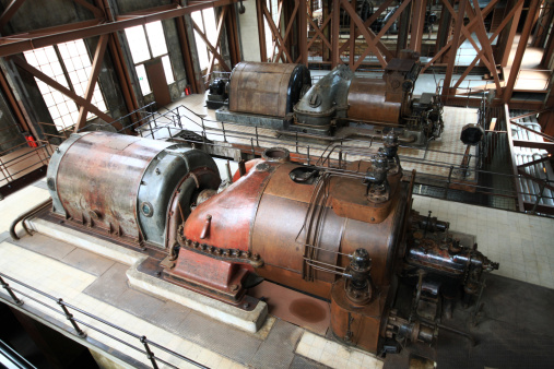 Antique electric generators of an old power plant.. The electric power is generated by the transfer of rotation energy from steam turbines into coiled turbine rotors, which are mounted on steam turbines.