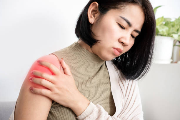 азиатская женщина страдает от замерзшего плеча с болью и скованностью - rotator cuff стоковые фото и изображения