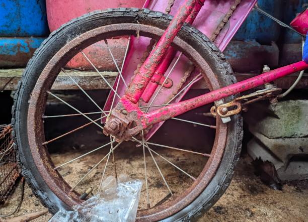 a pink children's bicycle that is old and rusty with rusty wheel and chain iron spokes