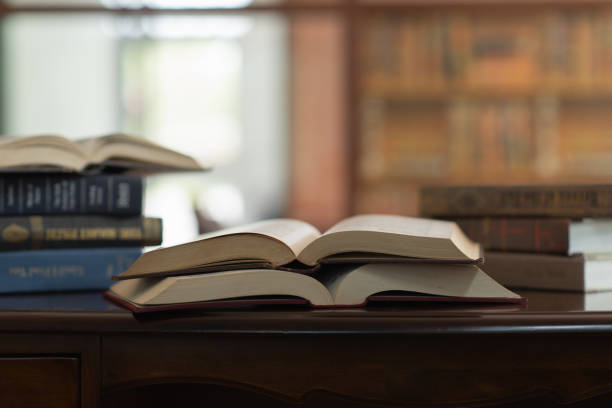 open book and books stacked on desk in library. legal education or law jurisprudence learning.