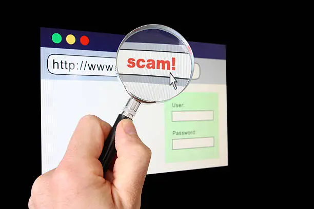 A hand holds a magnifying glass over the location bar of a browser, revealing the URL is a "scam".