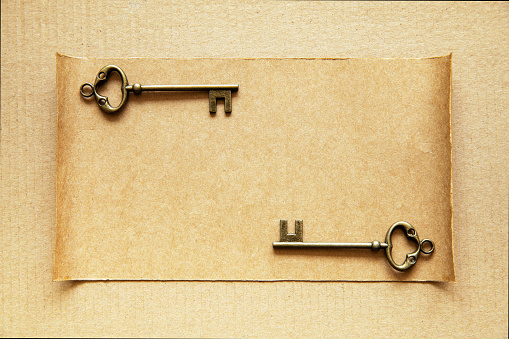 The old key lying on brown paper background. Copy space.