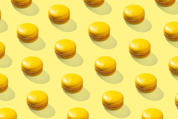 istock Lemon yellow macarons pattern on yellow background isolated with hard shadows 1472926337