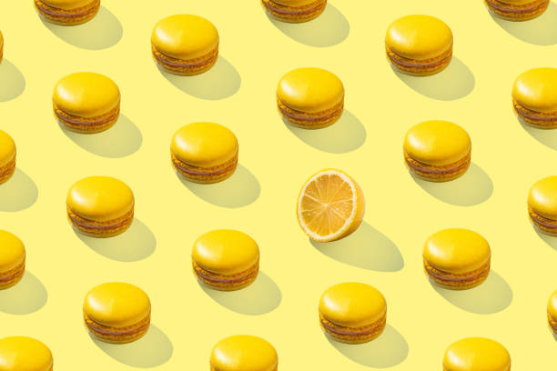istock Lemon yellow macarons pattern on yellow background isolated with hard shadows 1472926339