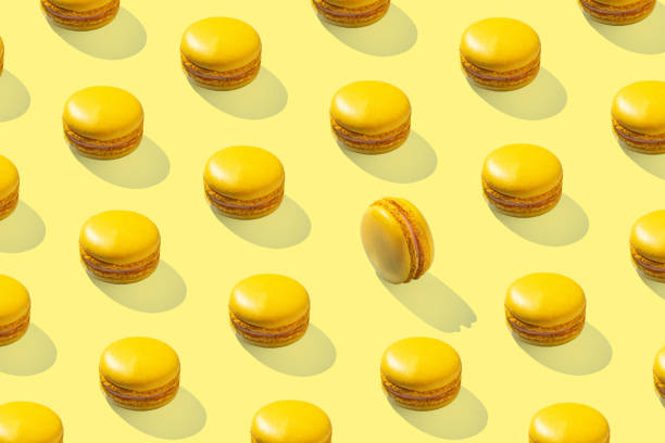 istock Lemon yellow macarons pattern on yellow background isolated with hard shadows 1472926343