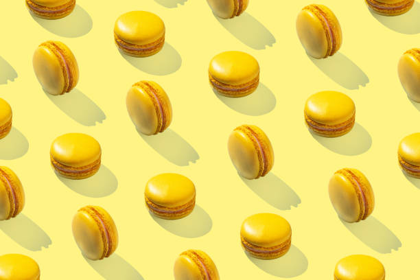 istock Lemon yellow macarons pattern on yellow background isolated with hard shadows 1472926347
