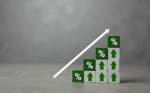 Green wooden cubes with icon percentage above arrow pointing up. The direction of an arrow symbolizing that the interest rates are going up. Economy is improving. Copy space