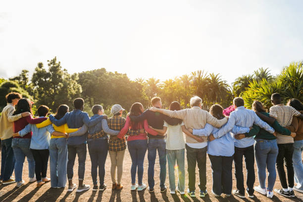Group of multigenerational people hugging each others - Support, multiracial and diversity concept - Main focus on senior man with white hairs stock photo