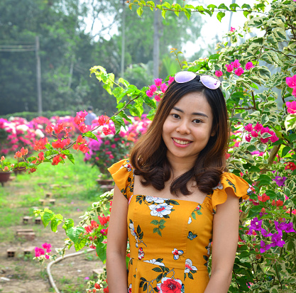 Young Asian woman standing at flower garden in spring time.