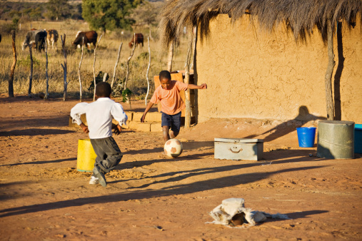 African children playing football at the village cattle post