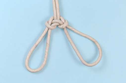 Rope knot Spanish bowline intended to lift a person, view from the front on a blue background
