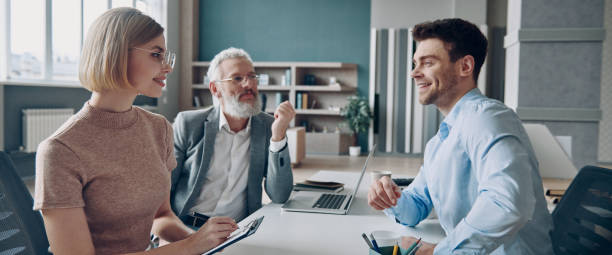 istock Cheerful young man having interview with HR managers while sitting at the office desk 1472940572