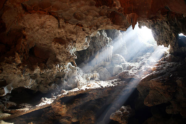 Heavenly Light Light bursting through an opening in a cave in Vietnam cave stock pictures, royalty-free photos & images