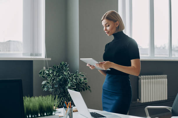 istock Confident young businesswoman using digital tablet while standing in the office 1472940953
