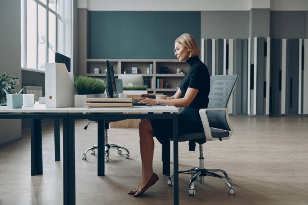 istock Serious young businesswoman using laptop while sitting at her working place in office 1472941044