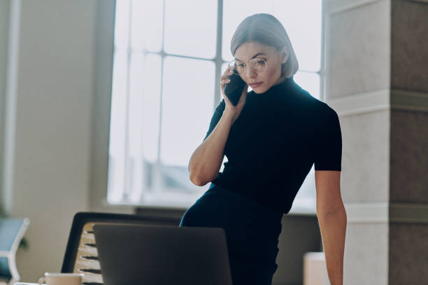 istock Confident young businesswoman talking on mobile phone while working in the office 1472941132