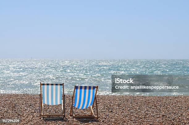 Two Blue And Yellow Deckchairs On A Shingle Beach By The Sea Stock Photo - Download Image Now