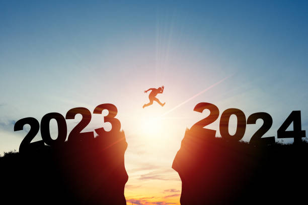 willkommen frohe weihnachten und ein glückliches neues jahr 2024, silhouette mann springt von 2023klippe zu 2024 klippe mit wolkenhimmel und sonnenlicht. - new years day stock-fotos und bilder