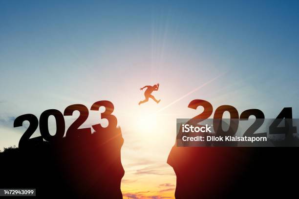 Welcome Merry Christmas And Happy New Year In 2024silhouette Man Jumping From 2023cliff To 2024 Cliff With Cloud Sky And Sunlight Stock Photo - Download Image Now